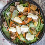 Salad with chicken nuggets, feta cream, croutons, carrots and cucumbers